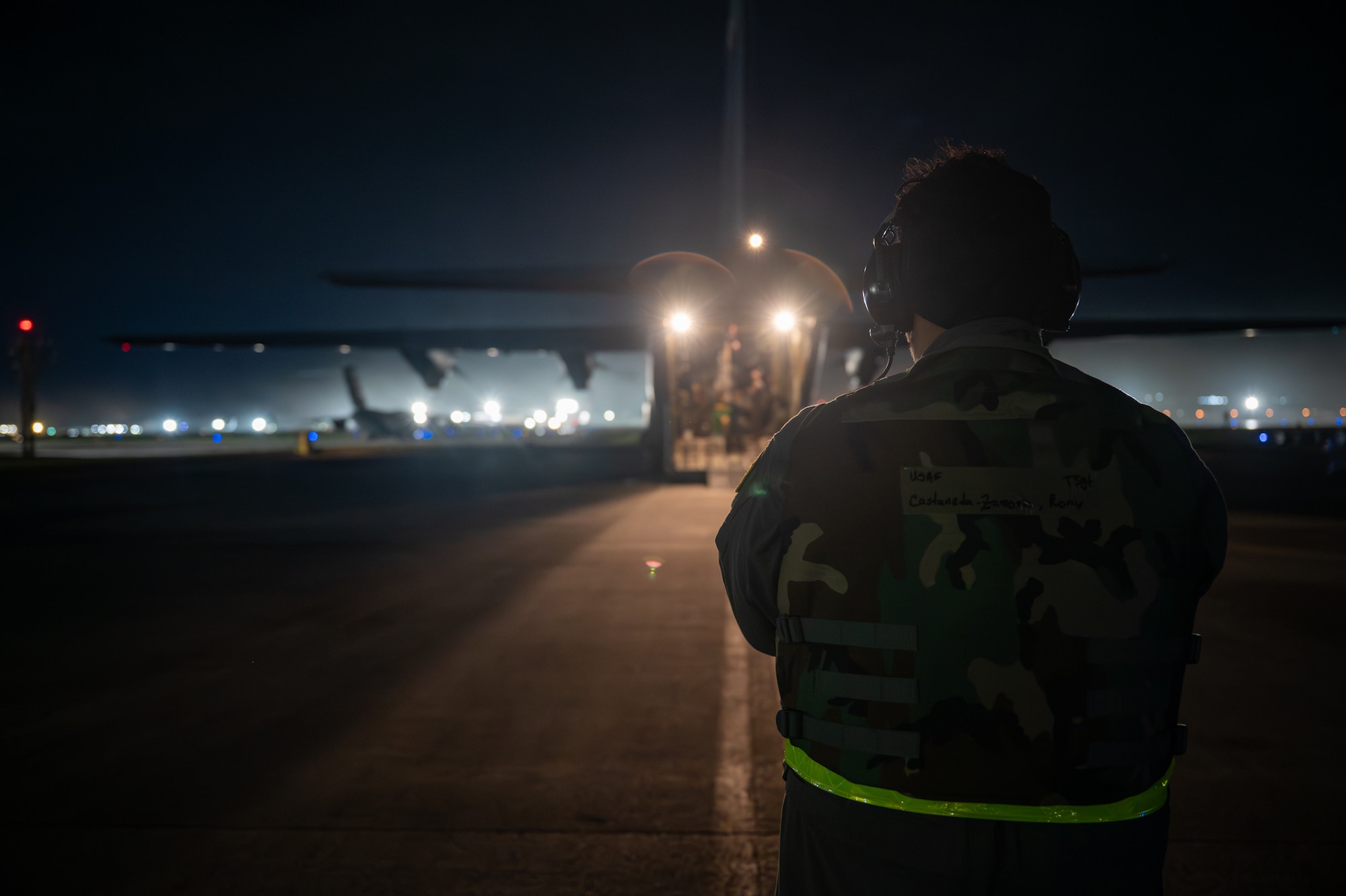 A service member stands in front of a C-130J Super Hercules, preparing to unload the aircraft