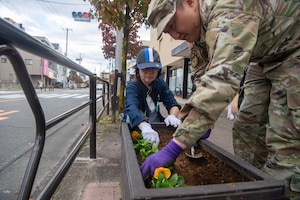 Two people plant flowers in a planter.