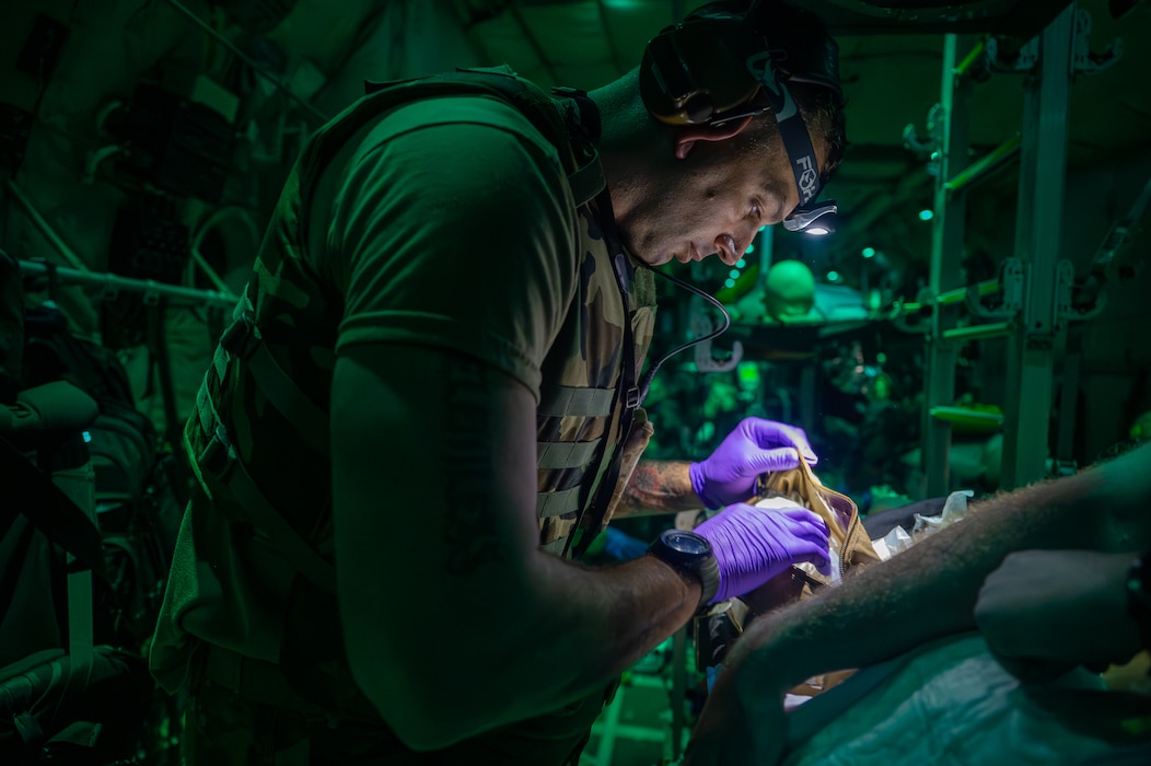 A service member prepares an IV for a patient.