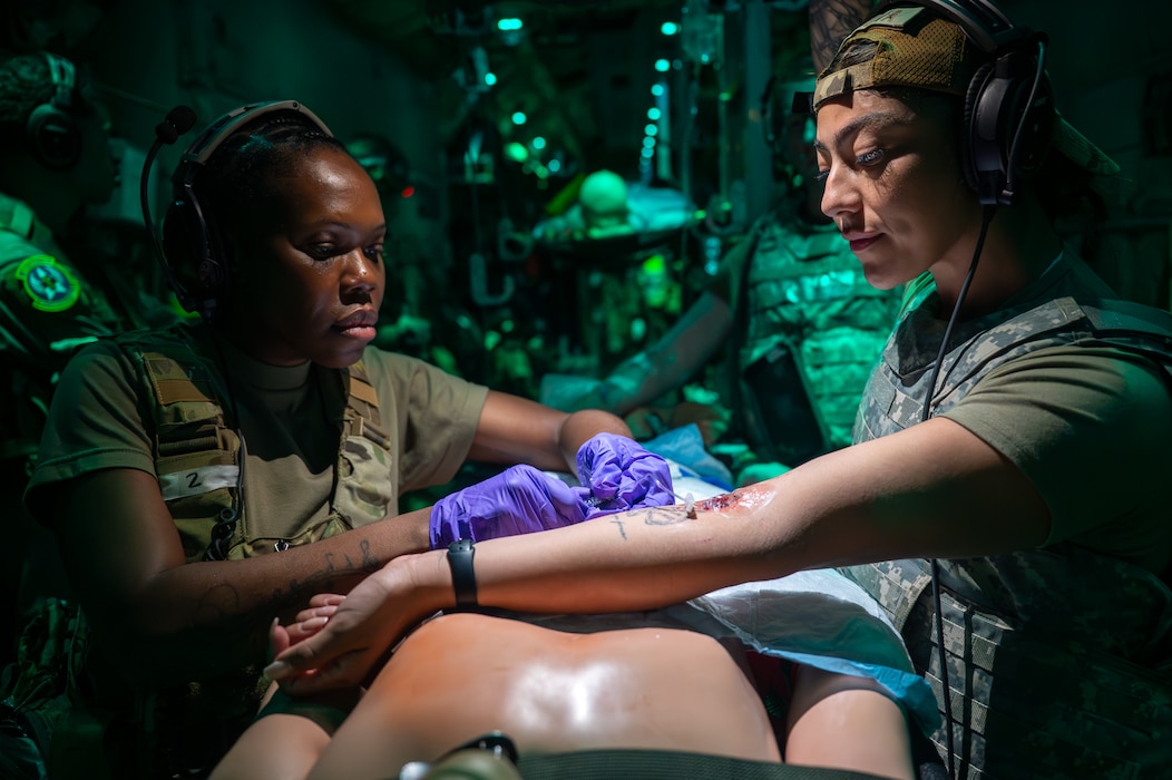 A service member inserts an IV into the arm of another service member.
