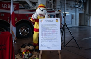 Sparky, 374th Civil Engineering Squadron fire dog, poses for a photo with the proclamation of Fire Prevention Week.
