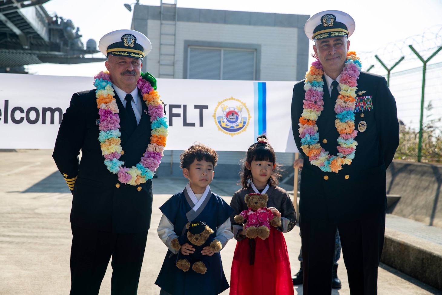 Rear Adm. Eric Anduze, right, commander, Carrier Strike Group 5, and Capt. Timothy Waits, commanding officer of Nimitz-class aircraft carrier USS George Washington (CVN 73), pose for a photo with Korean children during a welcoming ceremony at Busan Naval Base, Busan, Republic of Korea, Nov. 5, 2025.