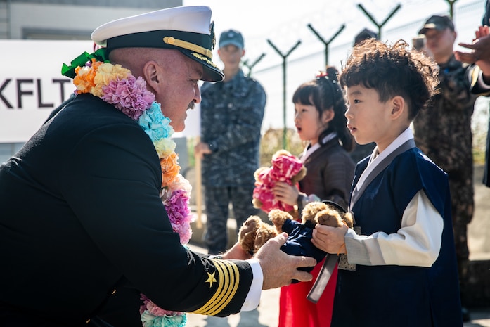 Capt. Timothy Waits, commanding officer of Nimitz-class aircraft carrier USS George Washington (CVN 73), exchanges gifts with a Korean child during a welcoming ceremony at Busan Naval Base, Busan, Republic of Korea, Nov. 5, 2025.