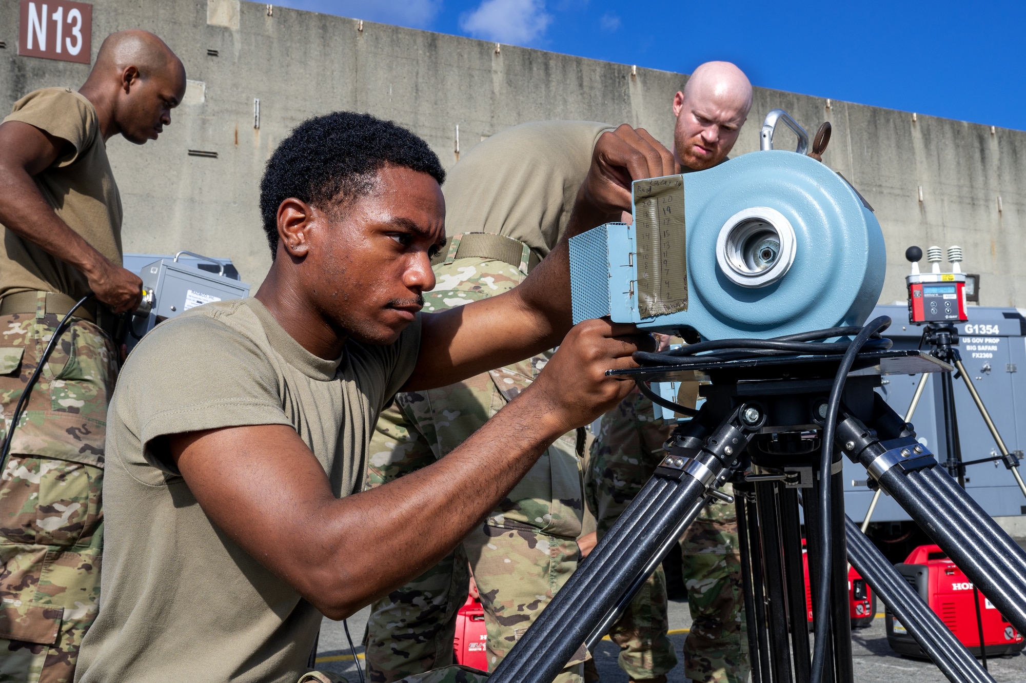 A service member works on a machine that helps with monitoring air quality.
