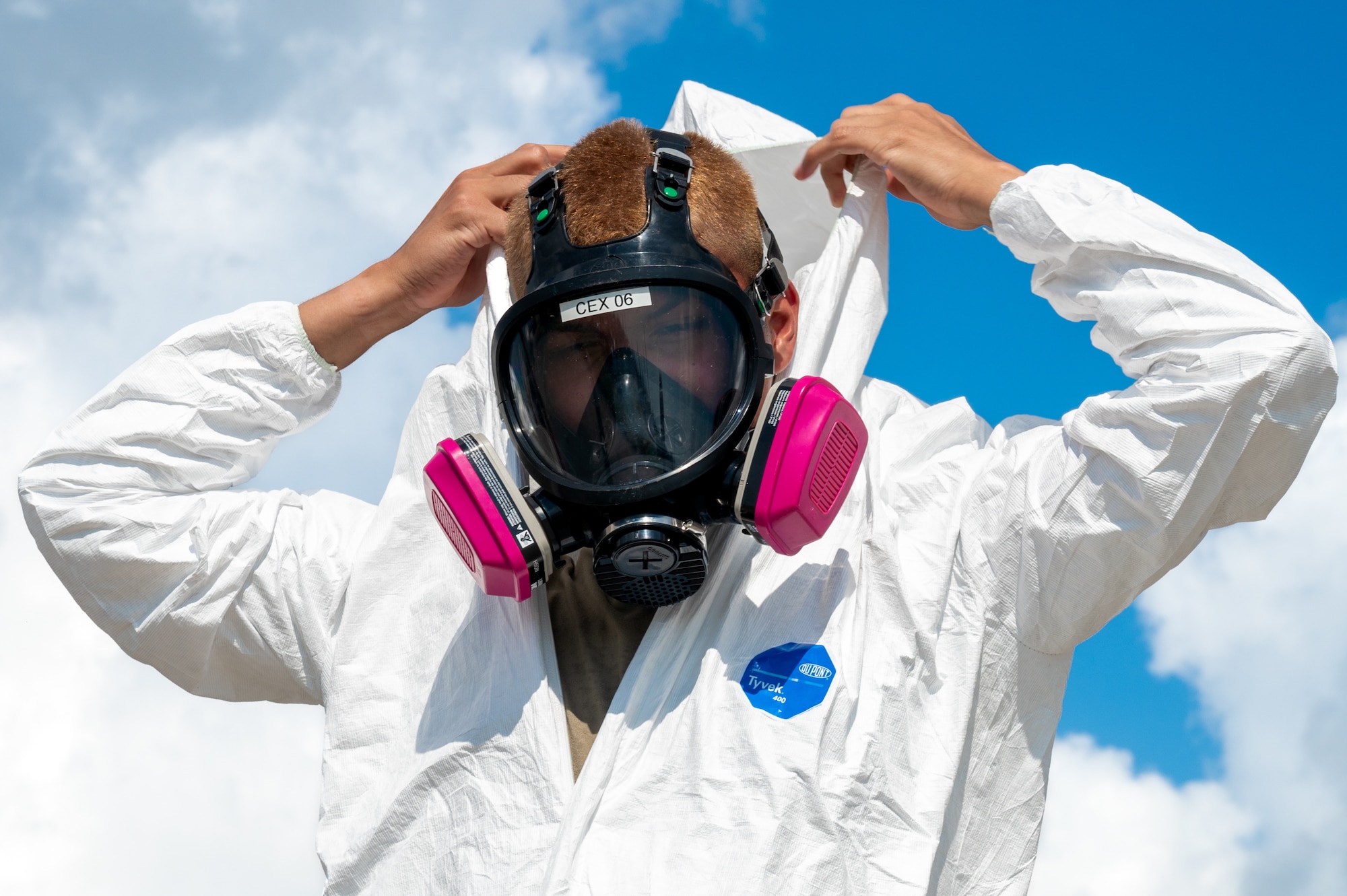 Service member puts on personal protective equipment during an exercise.