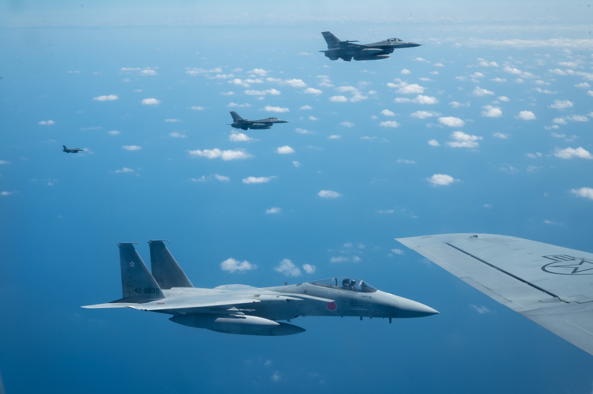 a side view of four aircraft flies together in a formation in the sky