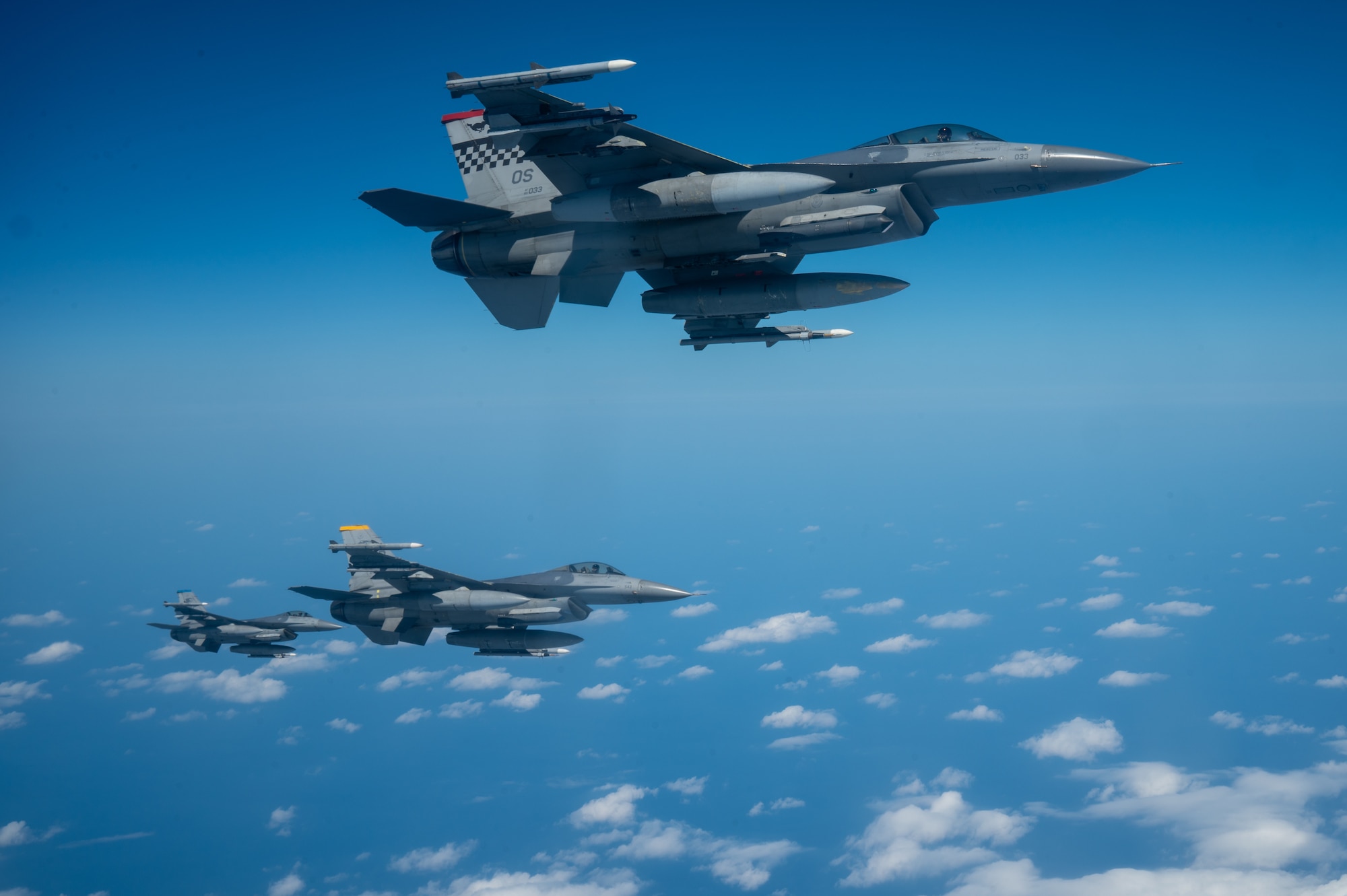 a side view of three aircraft flies together in a formation in the sky