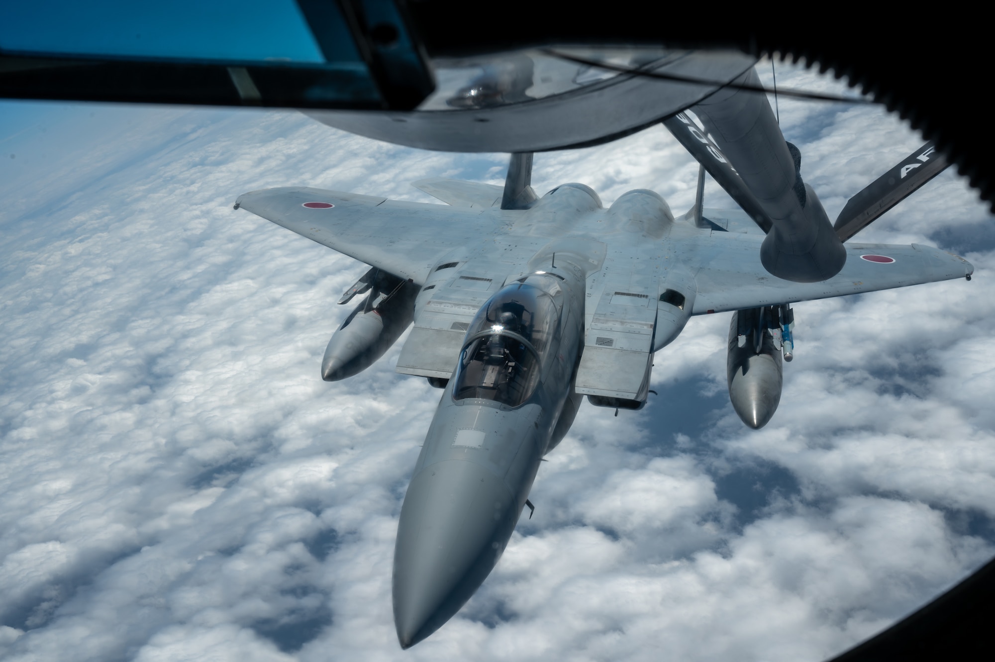 an aircraft flies towards the boom pod window for refueling