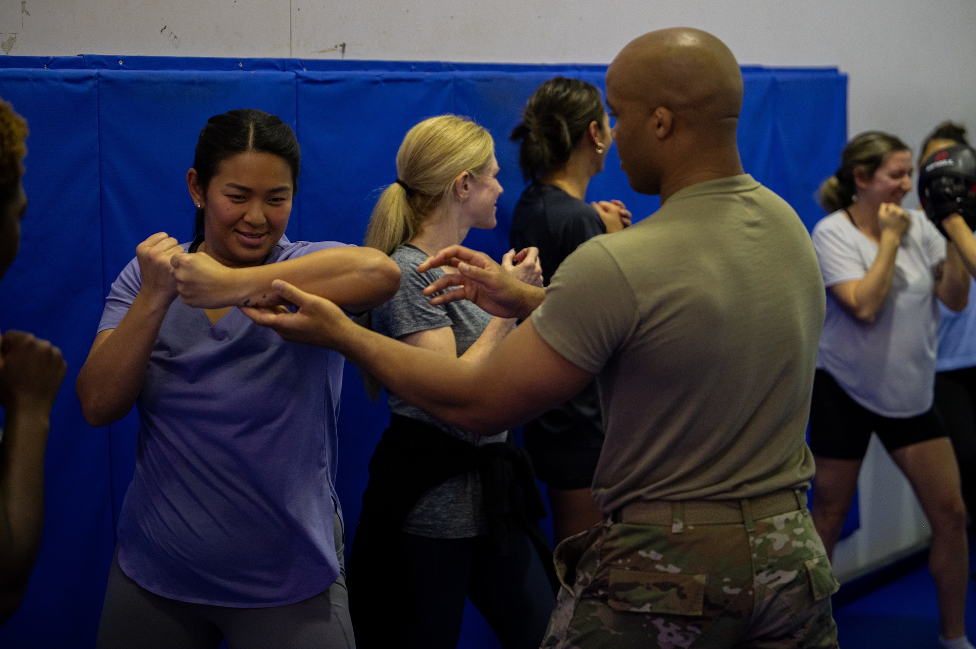 An Airman corrects the form of a participant during a self defense basics course.