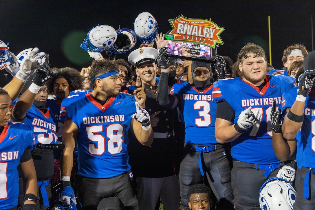 U.S. Marine Corps Staff Sgt. Erynn Hernandez, a recruiter with Marine Recruiting Sub Station Bay Brook, Recruiting Station South Texas, presents the Dickinson High School football team with the Great American Rivalry Series Trophy at Sam Vitanza Field in Dickinson, Texas Oct. 24, 2025. The Great American Rivalry Series high school football game, an event managed by Brainbox Intelligent Marketing that highlights some of the nation’s top football rivalries. Marines engaged with students and fans by hosting pull-up challenges, giving away t-shirts, and presenting awards to outstanding athletes and the winning team. (U.S. Marine Corps Photo by Cpl. Christian Salazar)