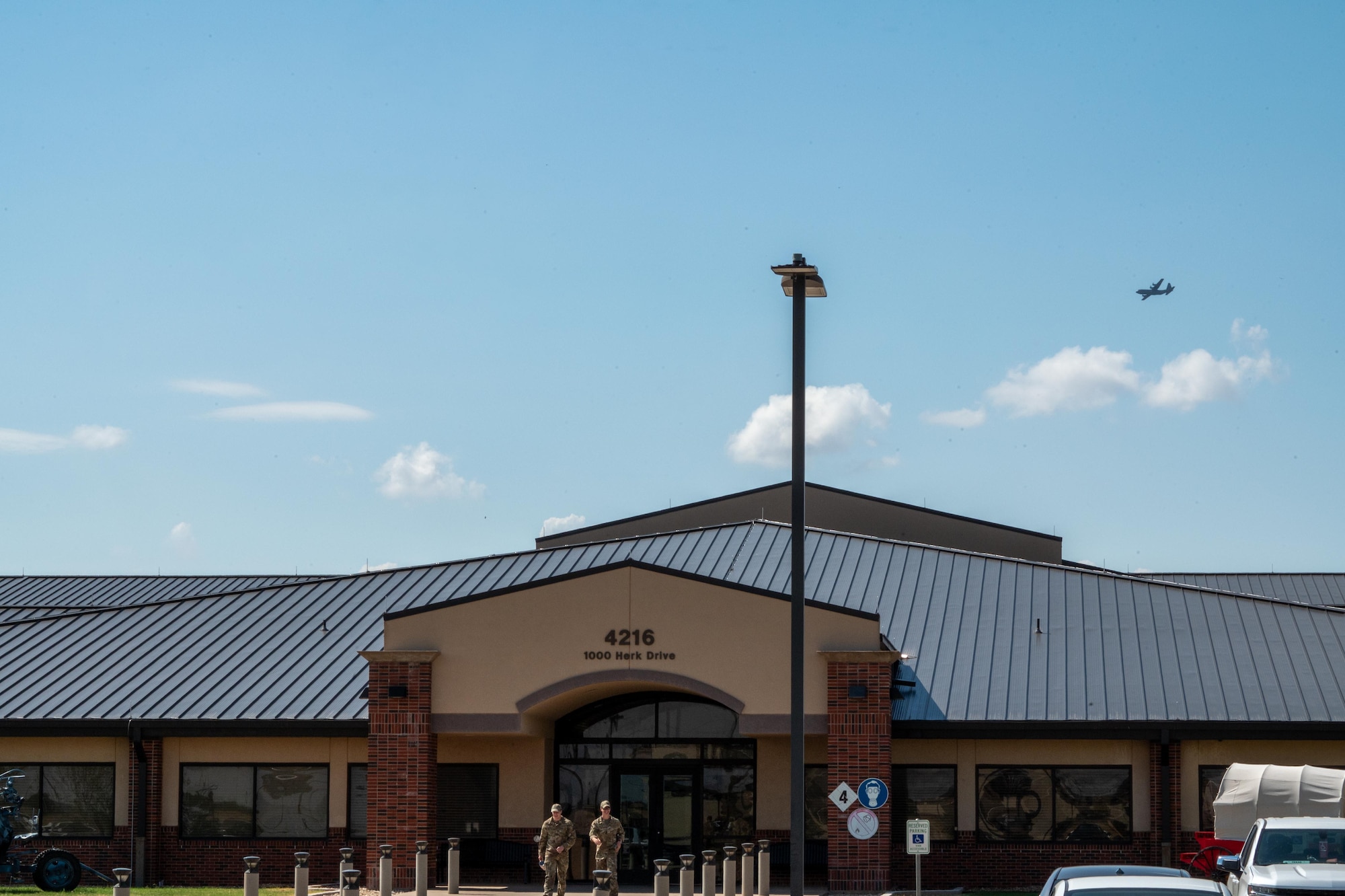A C-130 flie in the sky over a building