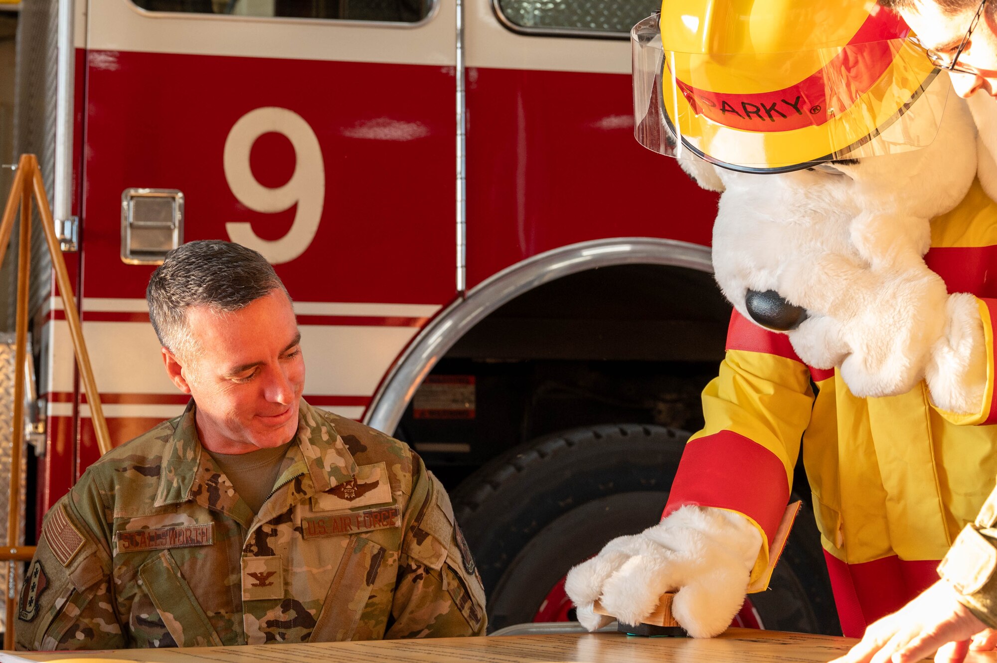 Sparky the Fire Dog, 7th Civil Engineer Squadron Fire Department mascot, joins U.S. Air Force Col. Ryan Stallsworth, 7th Bomb Wing deputy commander, in signing the 2025 Fire Prevention Week proclamation at Dyess Air Force Base, Texas, Oct. 2, 2025. The annual campaign encourages awareness and participation in fire safety education throughout the community. (U.S. Air Force photo by Airman William Neal)