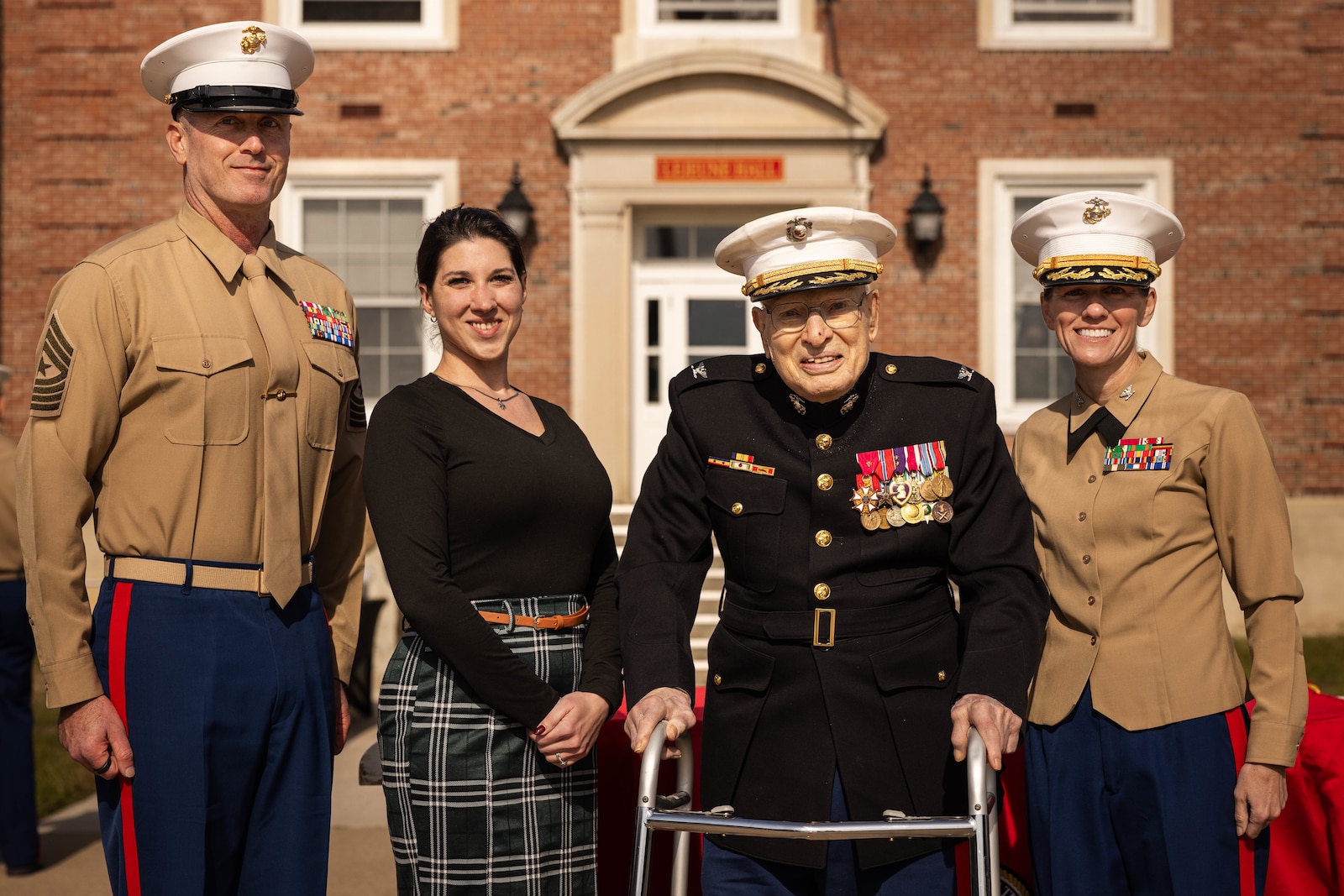 U.S. Marine Corps Sgt. Maj. Liam Williams, Sergeant Major of Marine Corps Base Quantico, left, veteran Sgt. Carley Vedro, the youngest Marine in attendance, retired Col. Frank Harris III, the oldest Marine in attendance, and Col. Jenny Colegate, base commander of MCB Quantico, pose for a photo during the Marine Corps cake cutting ceremony in honor of the 250th Marine Corps birthday at Lejeune Field on MCB Quantico, Virginia, Nov. 7, 2025. The ceremony honors the oldest and youngest Marine in attendance, representing the passing of tradition between generations of Marines. The annual celebration is a long-standing tradition which celebrates the establishment of the United States Marine Corps on Nov. 10, 1775, and honors the service and sacrifice of all Marines, past and present. (U.S. Marine Corps photo by Lance Cpl. Harleigh Faulk)
