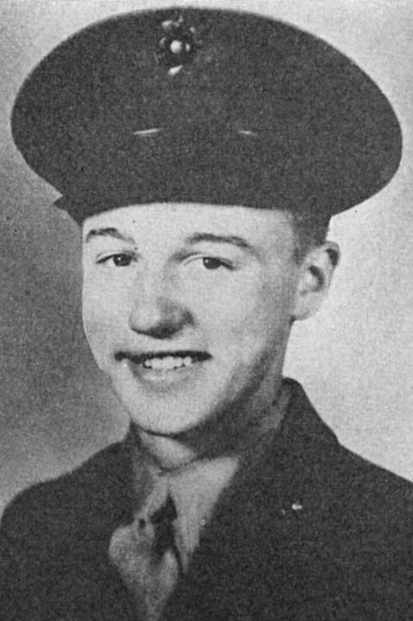 A man wearing a military dress uniform and cap poses for a photo.