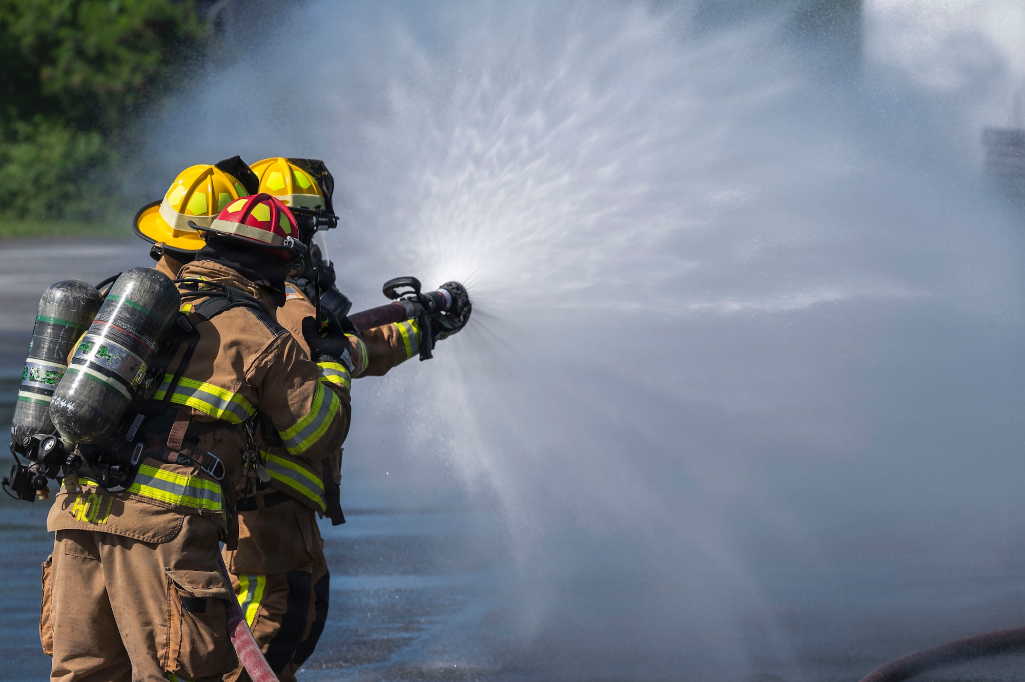 From left, U.S. Air Force Staff Sgt. Tevis Holi, 18th Civil Engineer Squadron Fire and Emergency Services Flight Lead Firefighter, Airman 1st Class Keahra Bailey, and A1C Andrews Morgan,18th CES firefighters, practice coordinated firefighting procedures during base-wide operational readiness exercise BH 26-1 at Kadena Air Base, Japan, Nov. 6, 2025.