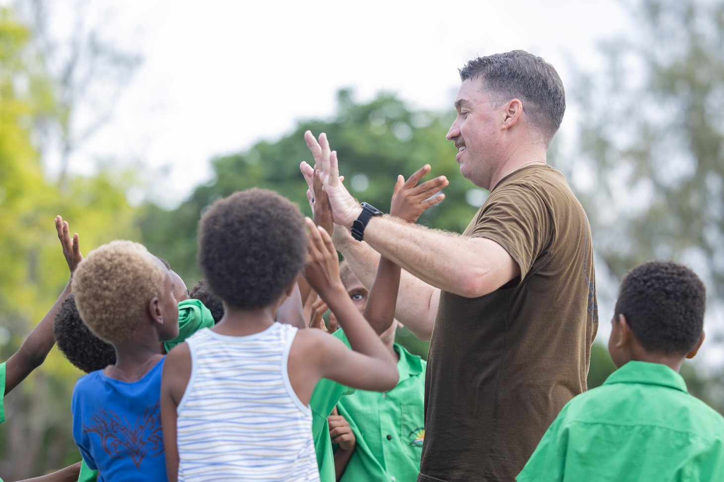 LUGANVILLE, Vanuatu (Nov. 10, 2025) – Lt. Cmdr. Dave Godkin high-fives students of East Santo School in Luganvile, Vanuatu, during a sports day and band performance in support of Pacific Partnership 2025, Nov. 10.