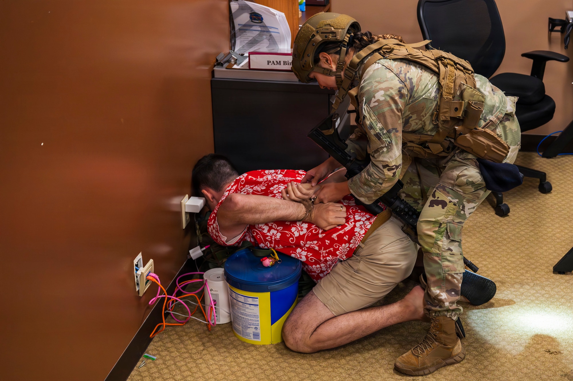 U.S. Air Force Senior Airman Viktoria Lacap, 18th Security Forces Squadron school resource officer, handcuffs Master Sgt. Rory, 18th Wing Inspector General superintendent, playing the role of a suspect, during a simulated active shooter exercise at Kadena Air Base, Japan, Nov. 4, 2025.