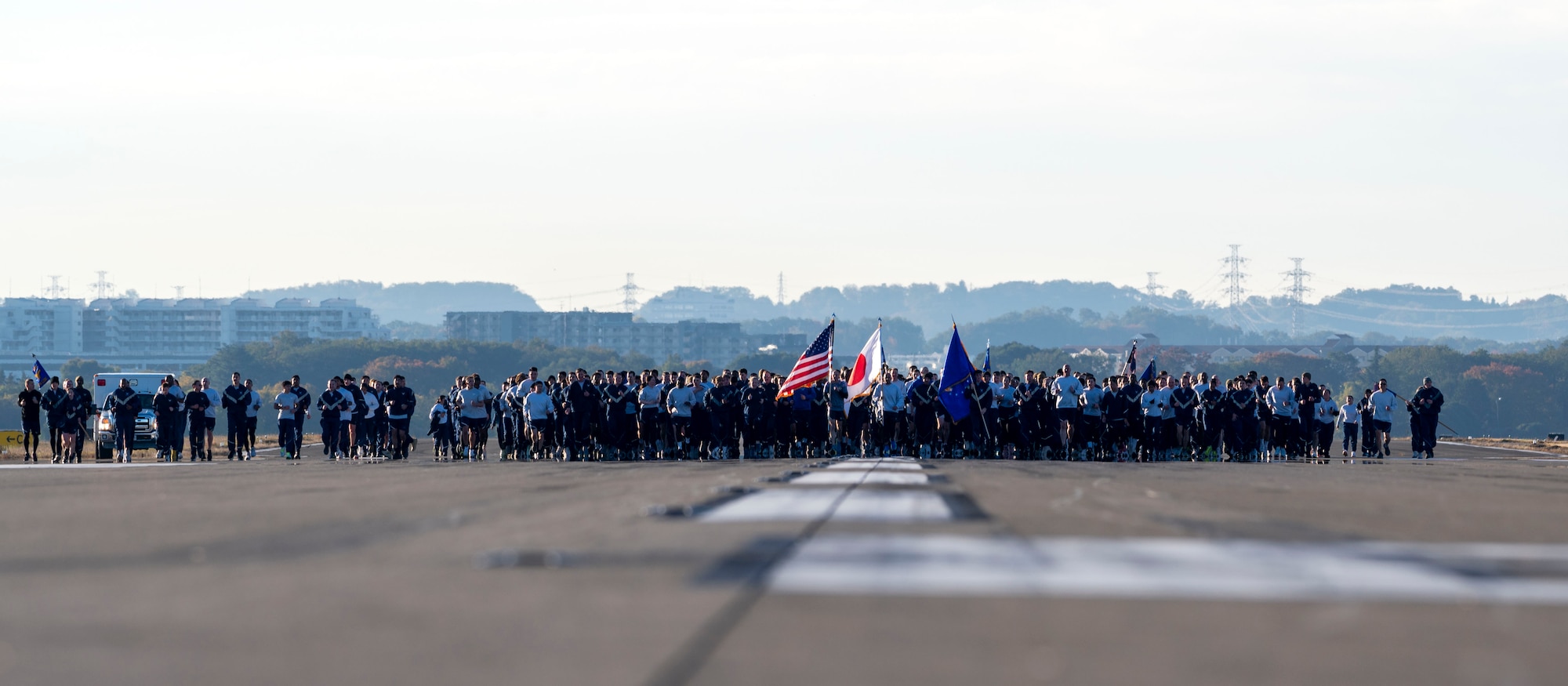 Military members in pt uniform jog down the runway.
