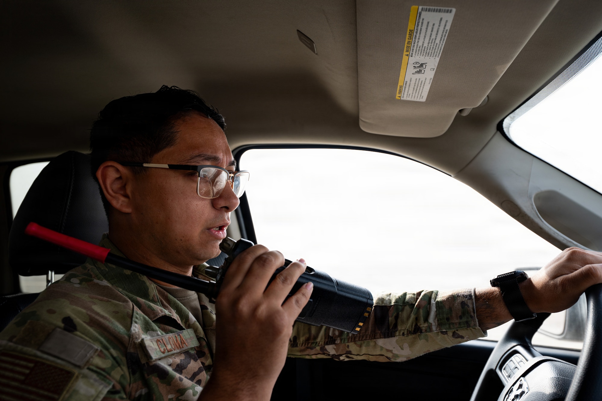 uniformed man sits in car and speaks on radio
