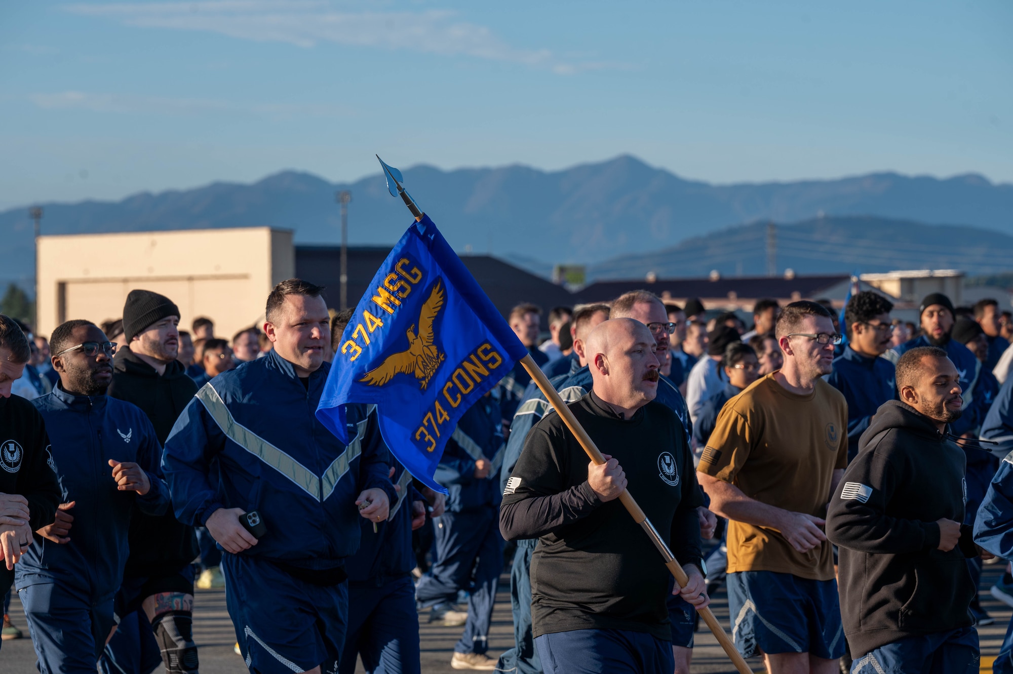 Military members in pt uniform run on the flightline.