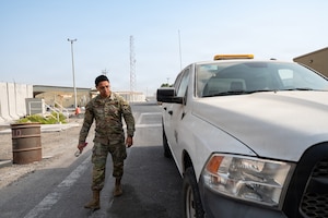 Uniformed man walks next to car