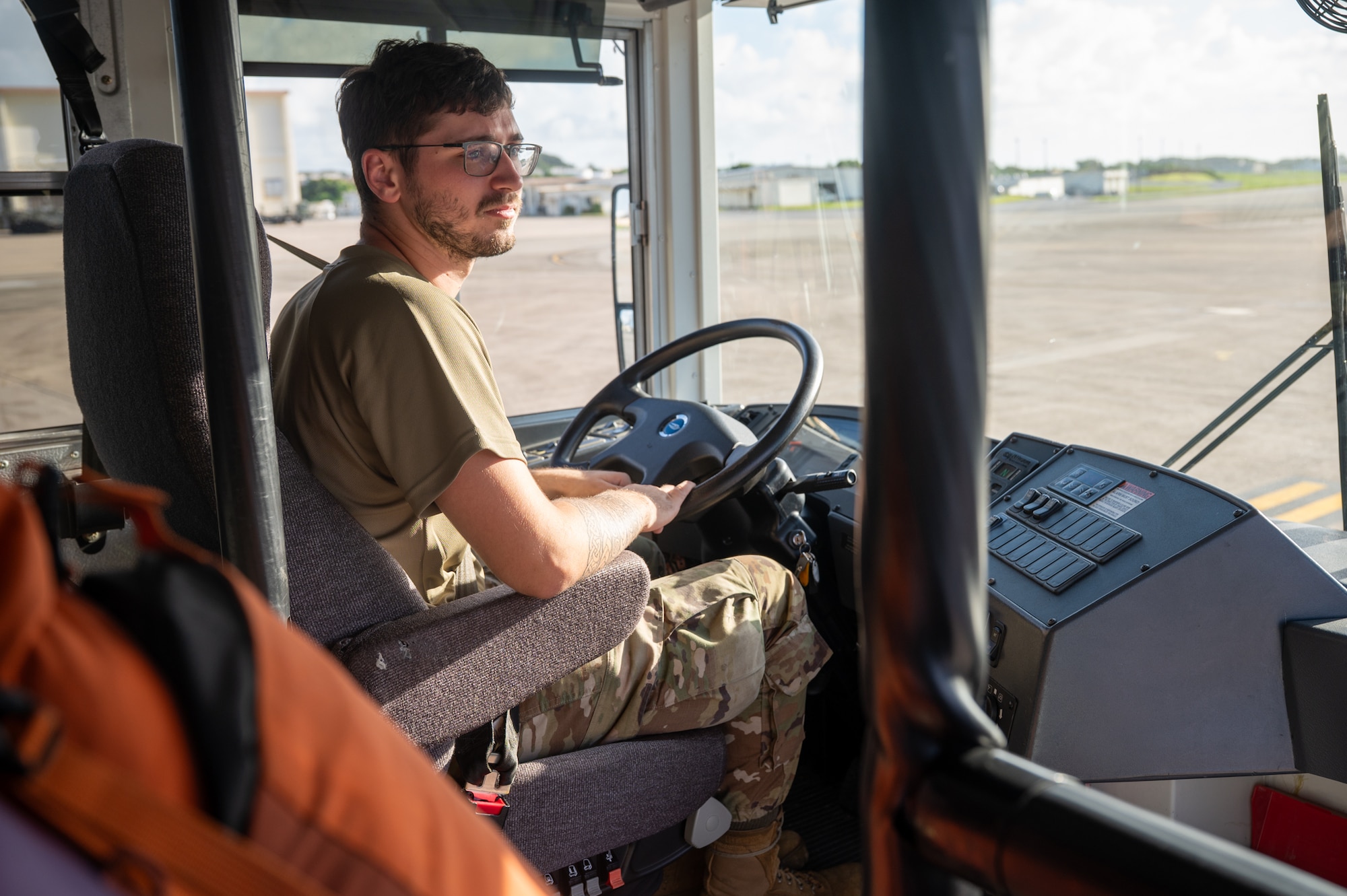 A service member sits at the driver's seat on a bus.