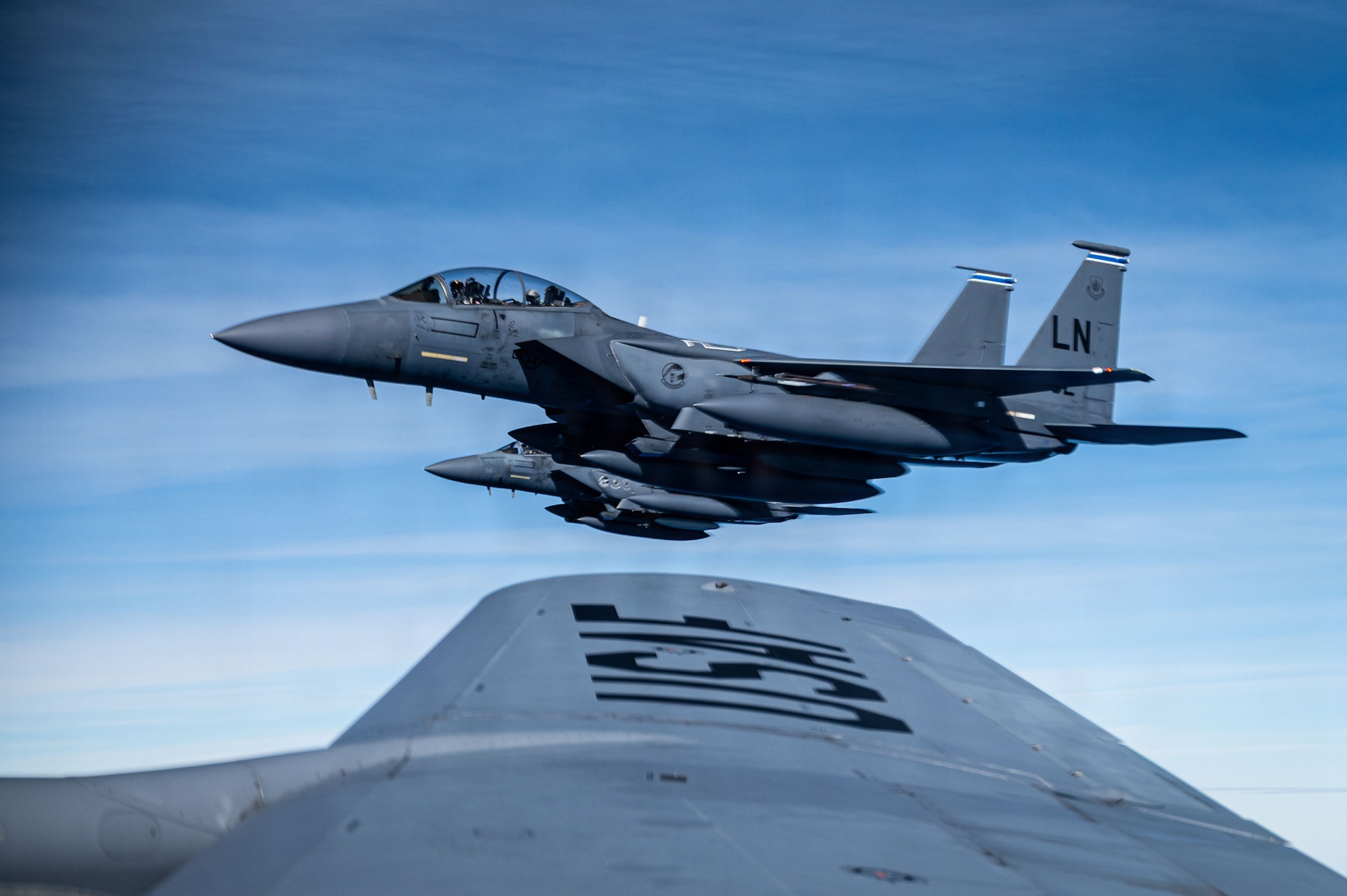 A U.S. Air Force F-15E Strike Eagle from the 48th Fighter Wing flies beside a KC-135 Stratotanker from the 100th Air Refueling Wing after receiving fuel during exercise Ocean Sky, over the Atlantic Ocean, Oct. 15, 2025.
