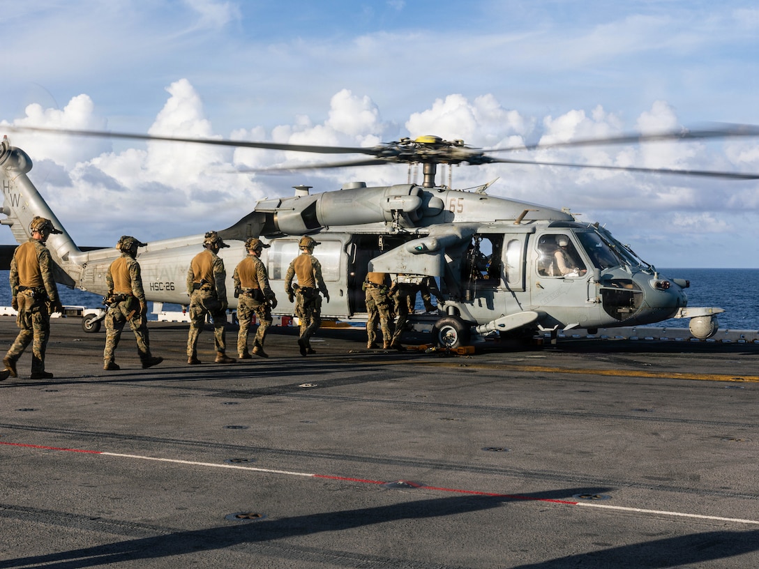 CARIBBEAN SEA – U.S. Marines with the Maritime Special Purpose Force, 22nd Marine Expeditionary Unit (Special Operations Capable), enter a board a U.S. Navy MH-60S Sea hHawk helicopter with Helicopter Sea Combat Squadron (HSC) 26, Iwo Jima Amphibious Ready Group, during fast rope insertion drills while aboard the U.S. Navy Wasp-class amphibious assault ship USS Iwo Jima (LHD 7), IWOARG, while underway in the Caribbean Sea, Oct. 23, 2025. U.S. military forces are deployed to the Caribbean in support of the U.S. Southern Command mission, Department of War-directed operations, and the president’s priorities to disrupt illicit drug trafficking and protect the homeland. (U.S. Marine Corps photo by Sgt. Tanner Bernat)