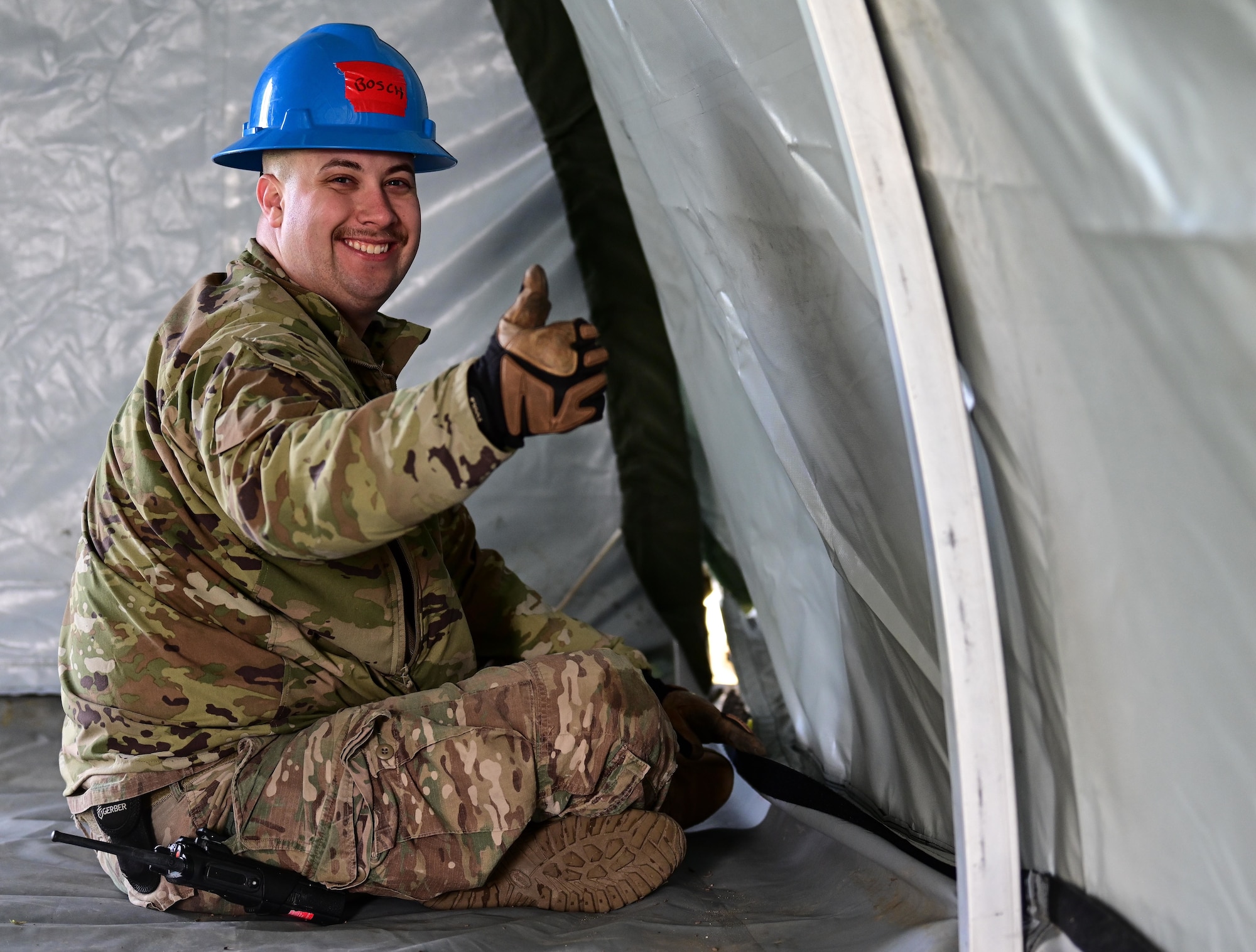 U.S. Air Force Staff Sgt. Justin Bosch, 100th Civil Engineer Squadron heating, ventilation, and air conditioning non-commissioned officer, poses for a photo while assisting in building a tent for exercise King Bee at RAF Mildenhall, England, Oct. 28, 2025.