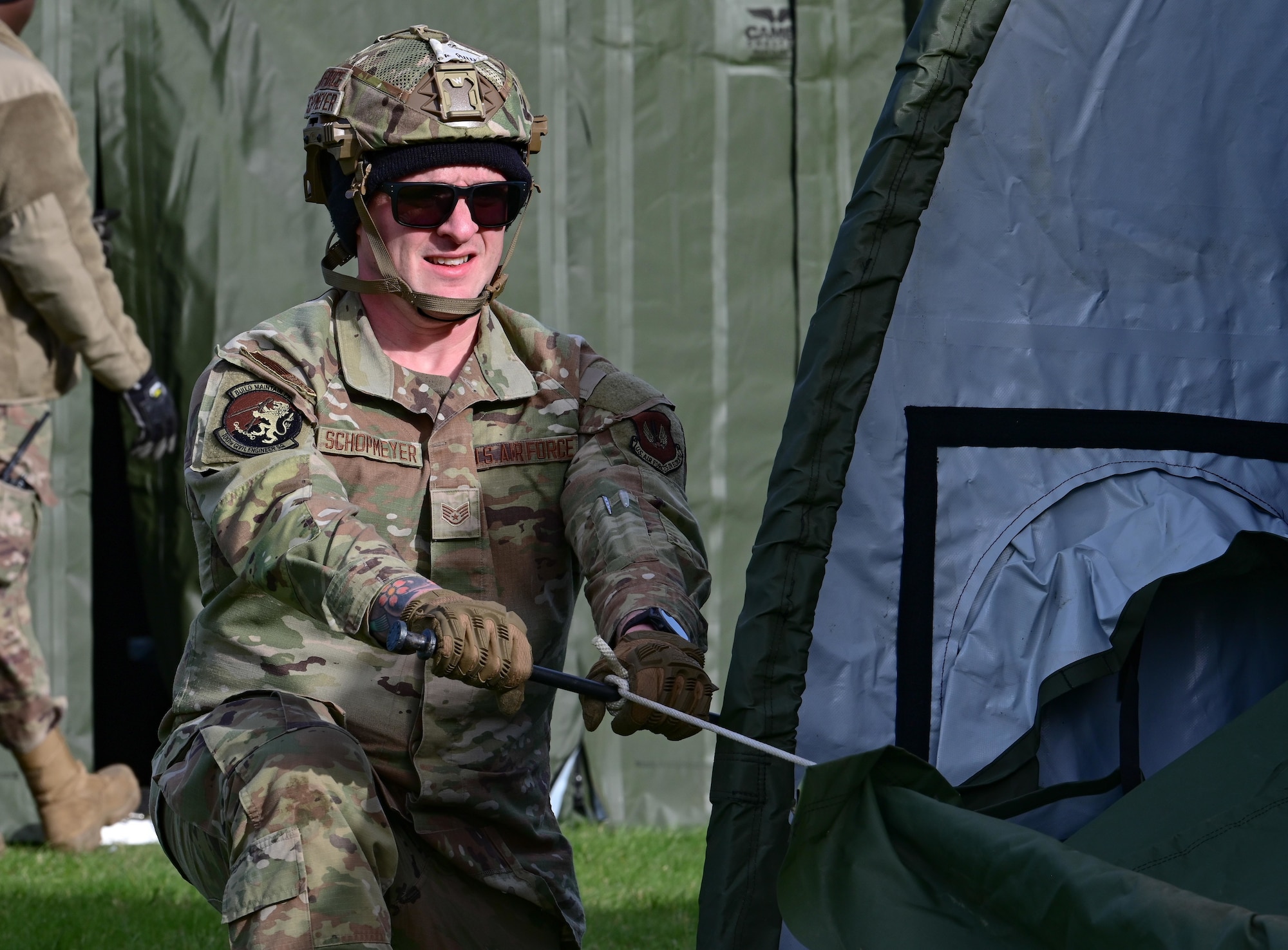 U.S. Air Force Staff Sgt. Phillip Schopmeyer, 100th Civil Engineer Squadron emergency management journeyman, assists in building a tent at RAF Mildenhall, England, Oct. 28, 2025.