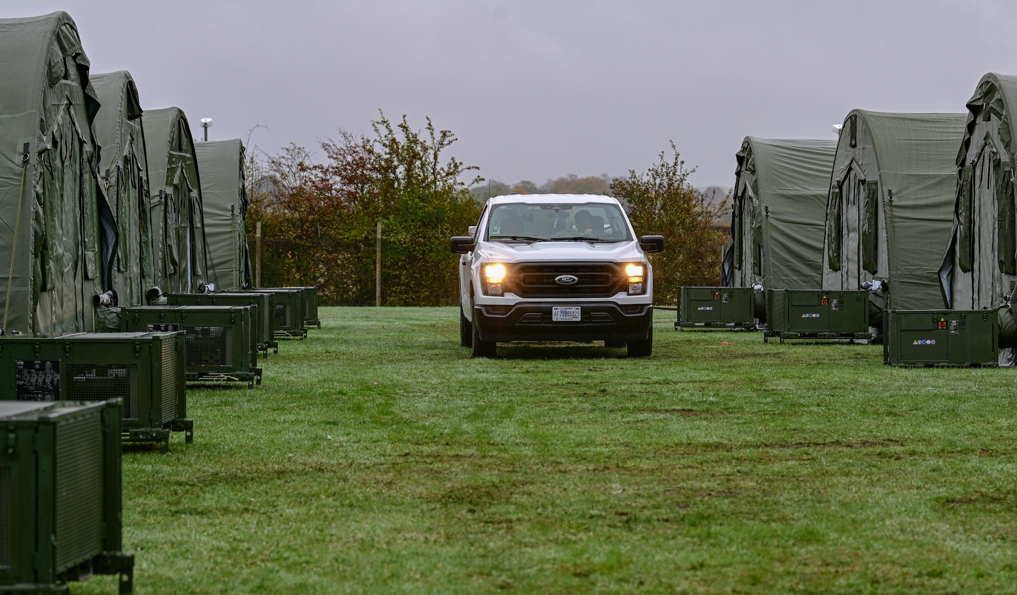 A 100th Civil Engineer Squadron vehicle tows a generator down the center aisle of a small shelter system during exercise King Bee at RAF Mildenhall, England, Oct. 29, 2025.