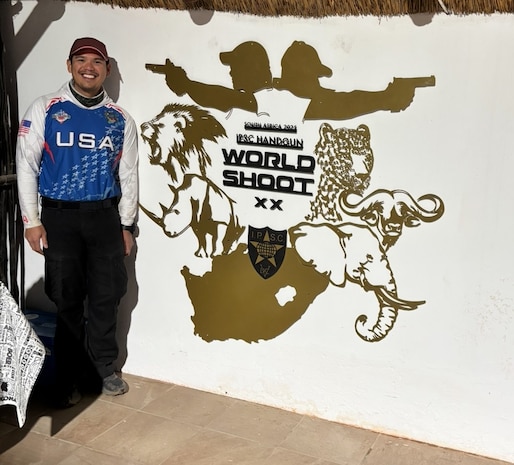 United States Air Force Tech Sgt. Dan Antonio Deladingco, 9th Mission Support Group (MSG) executive assistant, poses next to a sign for the 2025 International Practical Shooting Confederation (IPSC) Handgun World Shoot in Stilfontein, South Africa, Aug. 22, 2025.