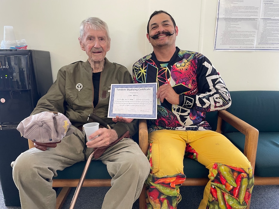 Two guys sitting holding a certificate.