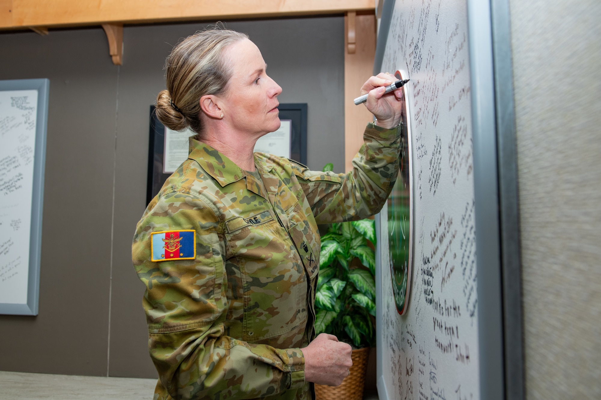 A uniformed woman signs a whiteboard