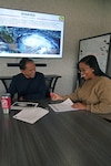 Andre Markham, USMEPCOM security specialist, and Govanni McCall, command emergency management officer, collaborate on establishing scenarios for a severe weather tabletop exercise (TTX).