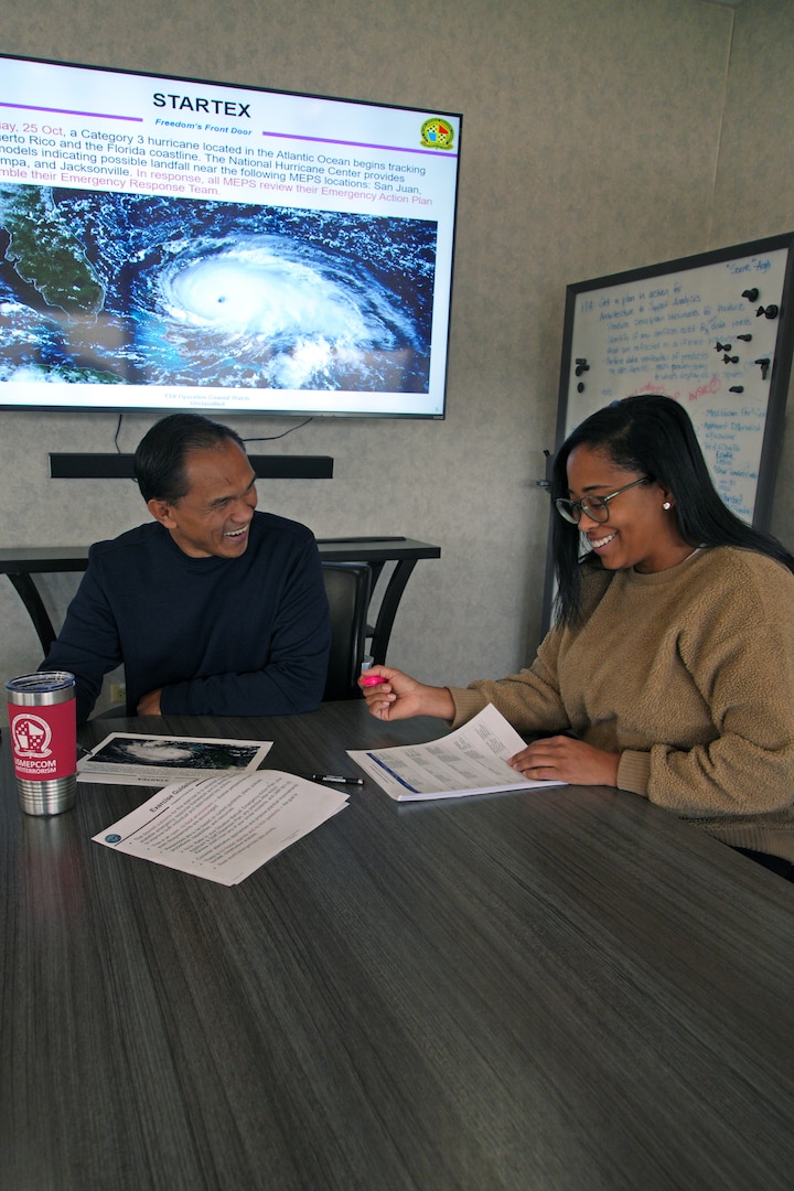 Andre Markham, USMEPCOM security specialist, and Govanni McCall, command emergency management officer, collaborate on establishing scenarios for a severe weather tabletop exercise (TTX).