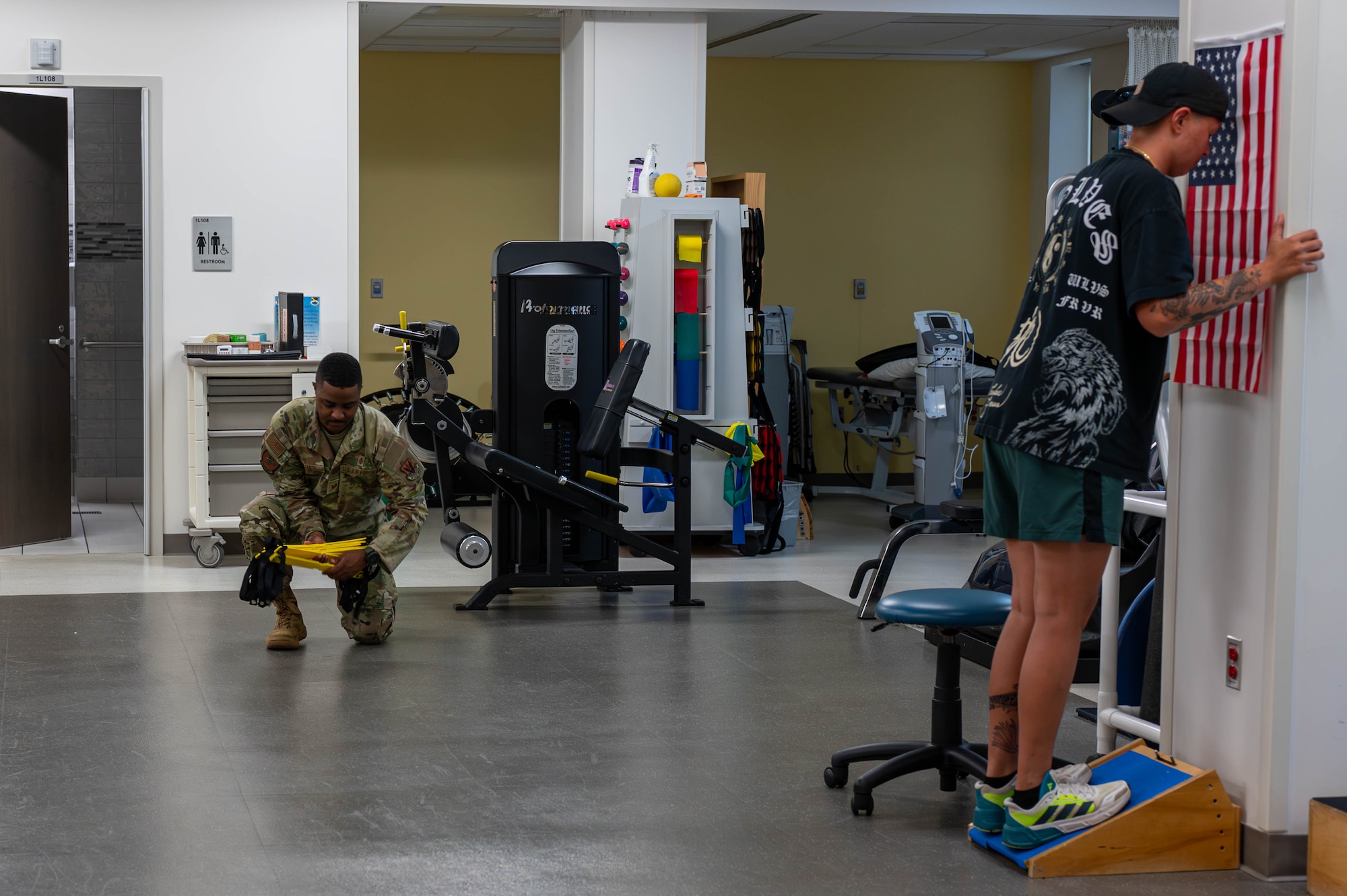 U.S. Air Force Tech. Sgt. Brandon Fisher, 325th Operational Medical Readiness Squadron human performance flight chief, left, picks up a foot ladder while working with a physical therapy patient at Tyndall Air Force Base.