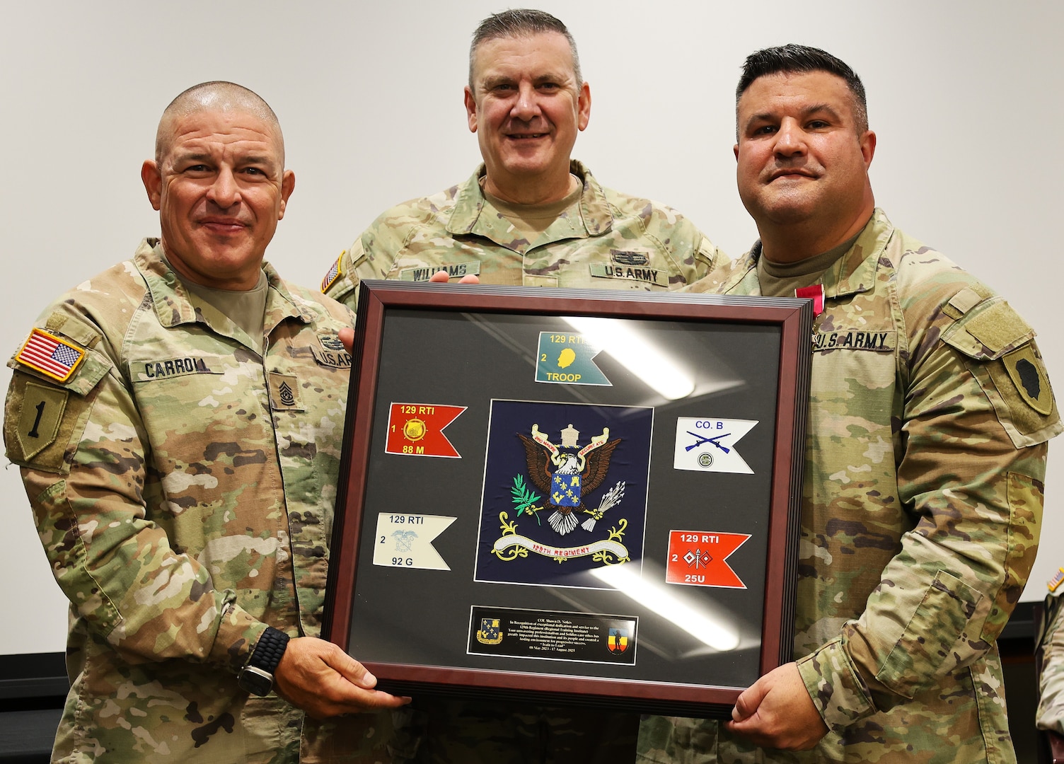 Command Sgt. Maj. Richard Carroll and Brig. Gen. Lenny Williams present outgoing 129th Regiment (Regional Training Institute) Commander Col. Shawn Nokes with a gift from the unit's Soldiers.