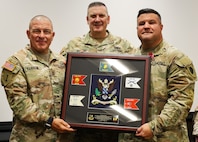 Command Sgt. Maj. Richard Carroll and Brig. Gen. Lenny Williams present outgoing 129th Regiment (Regional Training Institute) Commander Col. Shawn Nokes with a gift from the unit's Soldiers.