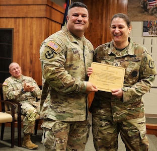 Col. Shawn Nokes presents Sgt. 1st Class Kayla Alberstett, a senior instructor in the 92G (culinary specialist) program, with the Gordon Ramsey award.