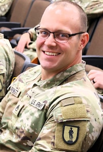 Staff Sgt. Aaron Barnett of the 129th Regiment (Regional Training Institute)  smiles after receiving a kickball from Col. Shawn Nokes.