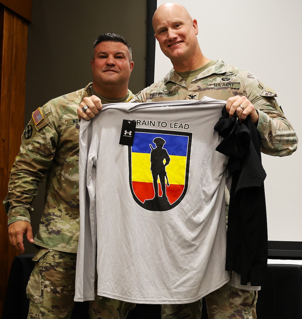 Col. Shawn Nokes, the outgoing commander of the 129th Regiment (Regional Training Institute), presents Col. Paul Metzdorff with some 129th RTI swag during the unit's Change of Command Ceremony.