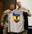 Col. Shawn Nokes, the outgoing commander of the 129th Regiment (Regional Training Institute), presents Col. Paul Metzdorff with some 129th RTI swag during the unit's Change of Command Ceremony.