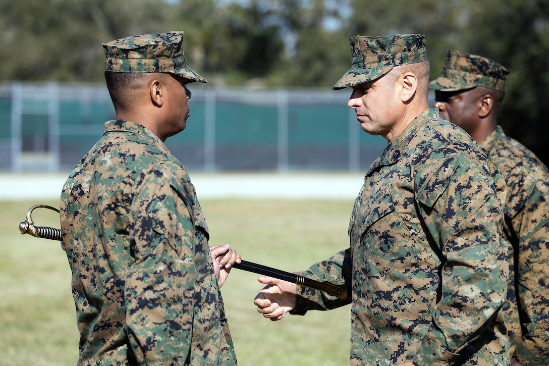 U.S. Marine Corps Col. David Merles, commanding officer of Blount Island Command, receives the sword of office from Sgt. Maj. Julian Lumm during the Nov. 14 relief and appointment ceremony at Marine Corps Support Facility Blount Island, Florida. Lumm is retiring after 30 years of service, and Merles passed the sword to Sgt. Maj. Shonor Burton, who assumed the senior enlisted leadership role. (Official Marine Corps Photo by Dustin Senger)