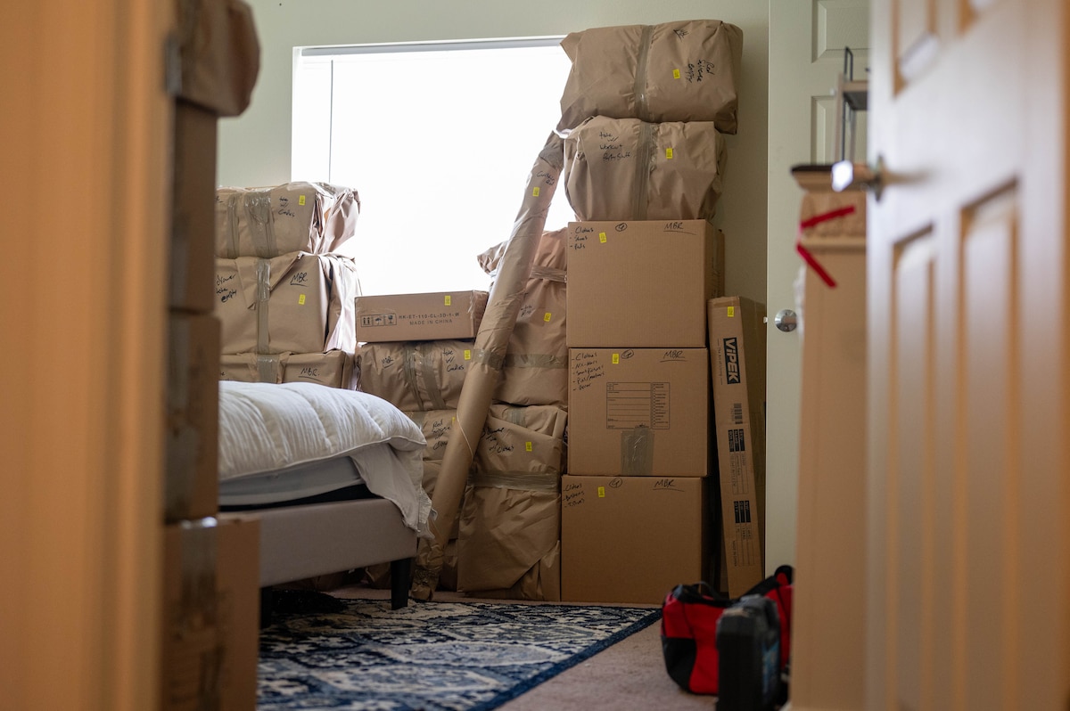 Boxes and wrapped furniture is tacked in a bedroom.