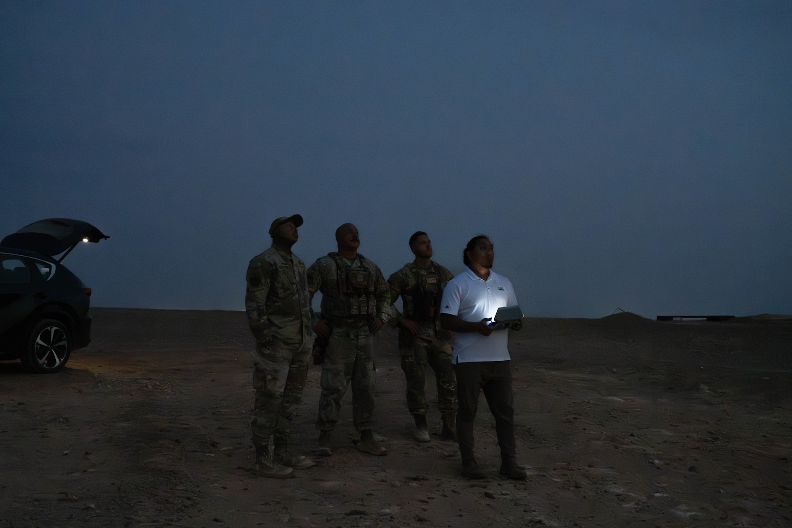 U.S. Air Force 332nd Expeditionary Security Forces Squadron small unmanned aircraft systems division members watch a Skydio quadcopter fly in the U.S. Central Command area of responsibility Nov. 4, 2025 2025. The sUAS team specializes in aerial defense through reconnaissance, target identification, and terrain observation by flying drones around base perimeters to better protect and defend personnel and assets. (U.S. Air Force photo by Senior Airman Kari Degraffenreed)