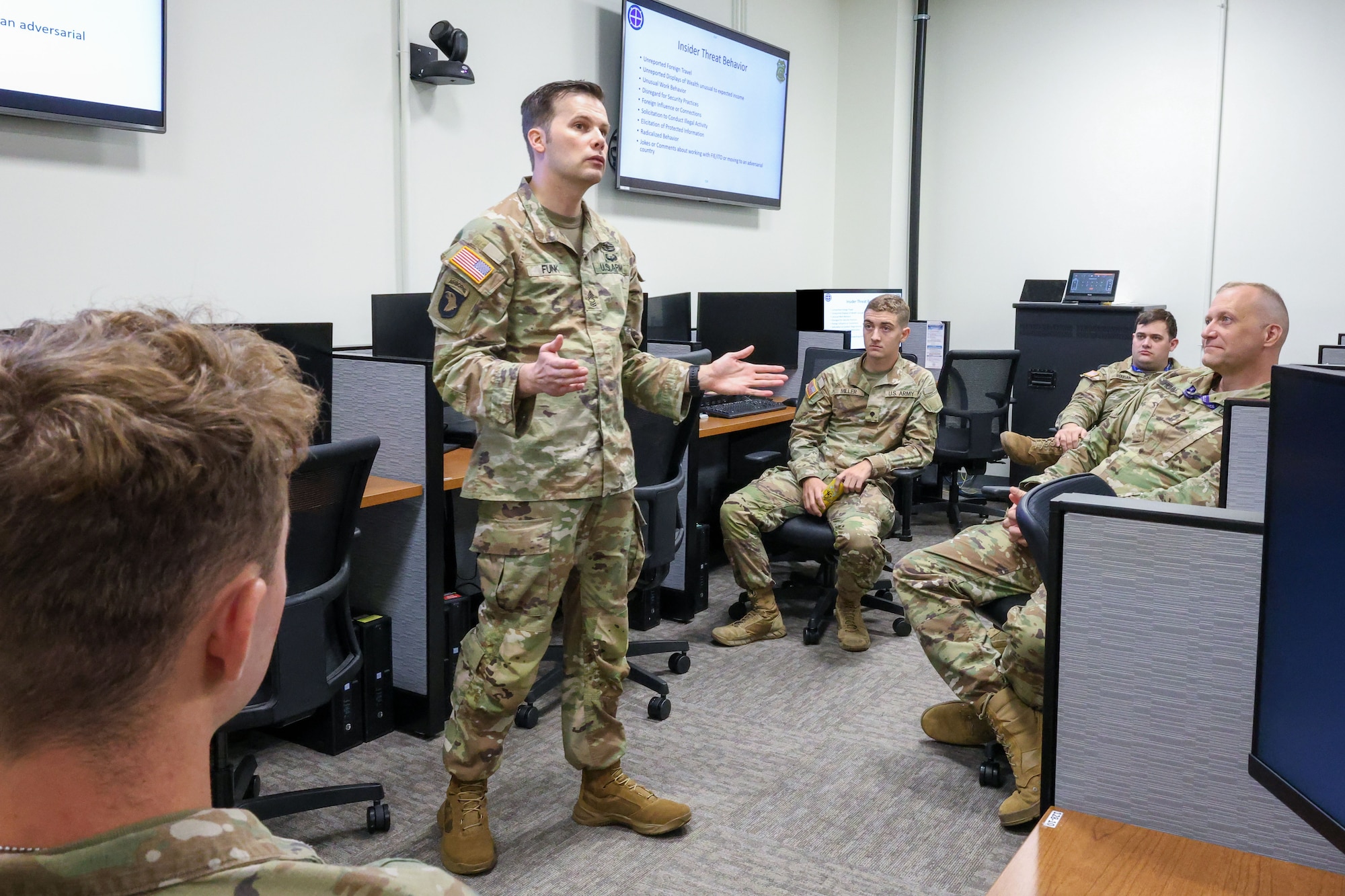 U.S. Army and Air Force troops gather in a classroom to exchange information. They are wearing OCP pattern uniforms.