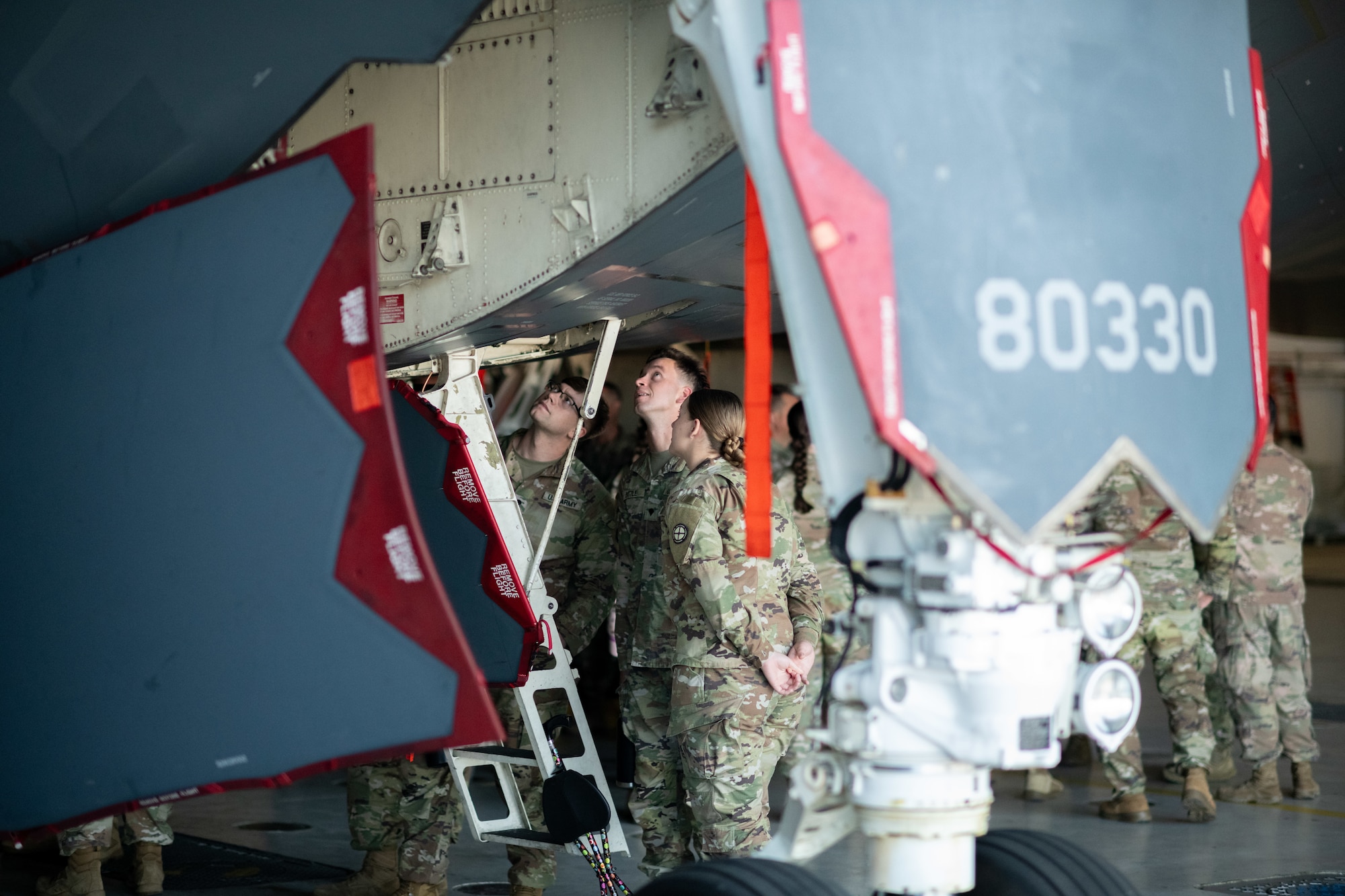 Missouri National Guard members look up the crew door of a B-2 Spirit stealth bomber during an orientation tour. The Guardsmen are wearing OCP pattern uniforms.