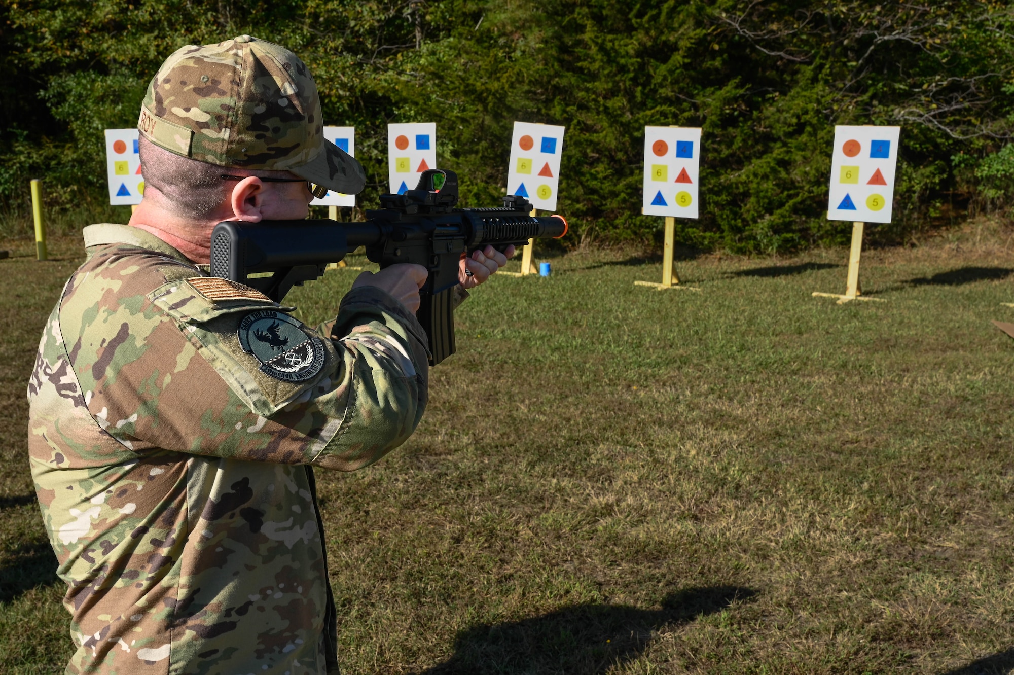 A man in uniform shoots at a target on a field.