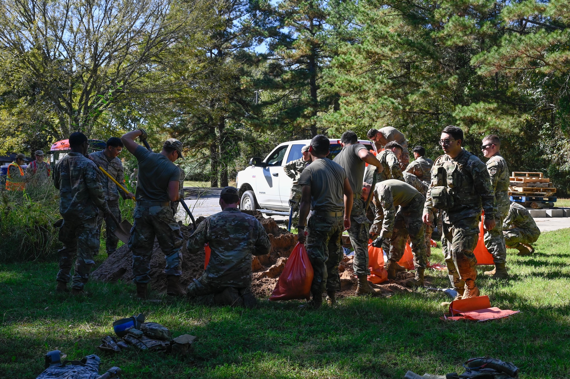 A group of people in uniform dig up a pile of sand.